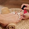 Process of applying bright red nail polish on toenails in beauty salon